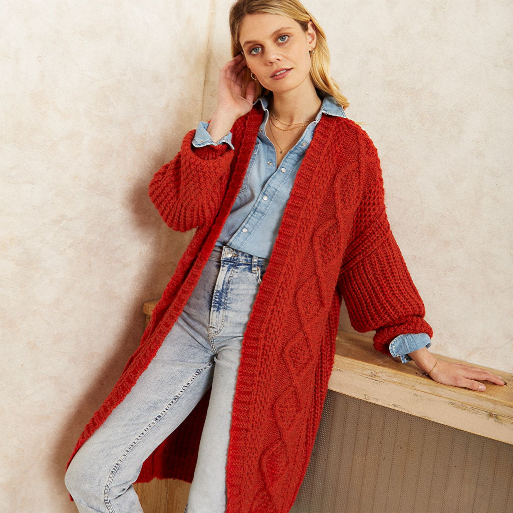 Woman wearing the Stevie long rust orange knitted cable weave cardigan and blue denim