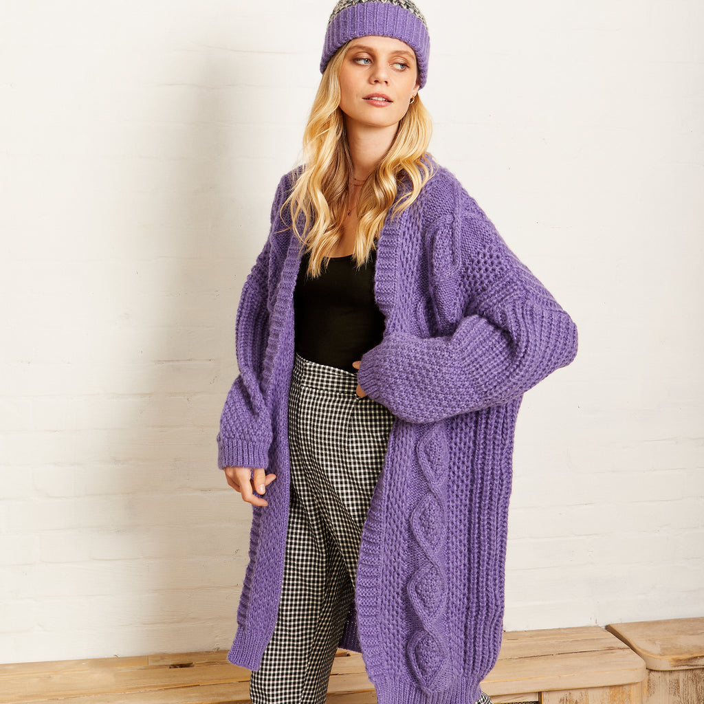 Woman posing in the Stevie lilac long cable knit cardigan and knitted bobble hat