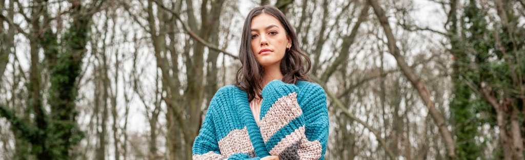 Photo of woman wrapped in a teal cardigan in the woods
