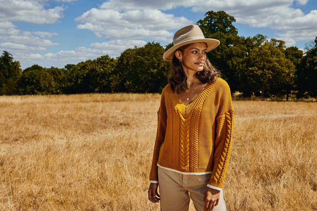 Woman standing in a field wearing a yellow knitted jumper